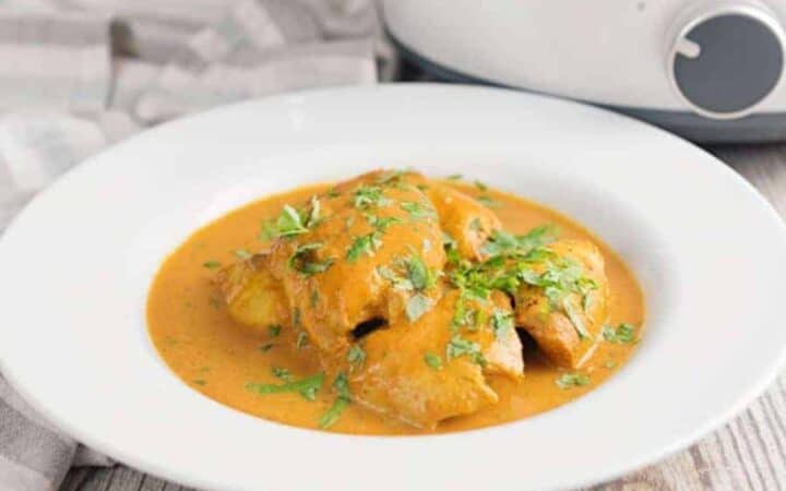 Side shot of slow cooker butter chicken in white dish.