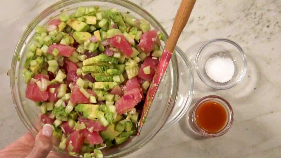 Mix together tuna, cucumber, avocado, and red onion in a glass mixing bowl for spicy tuna salad. 