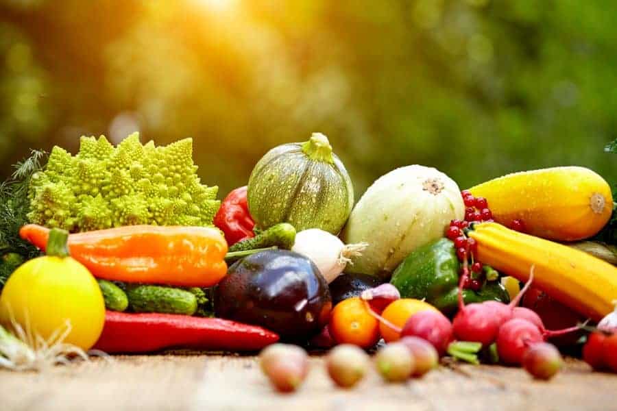 Fresh organic vegetables and fruits on wood table  in the garden