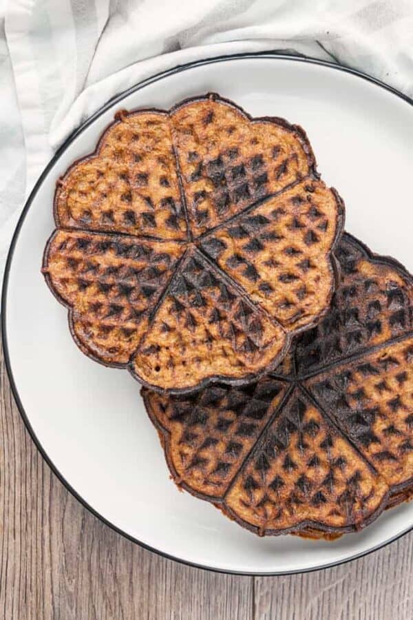 Two chocolate chaffles on a white plate overhead
