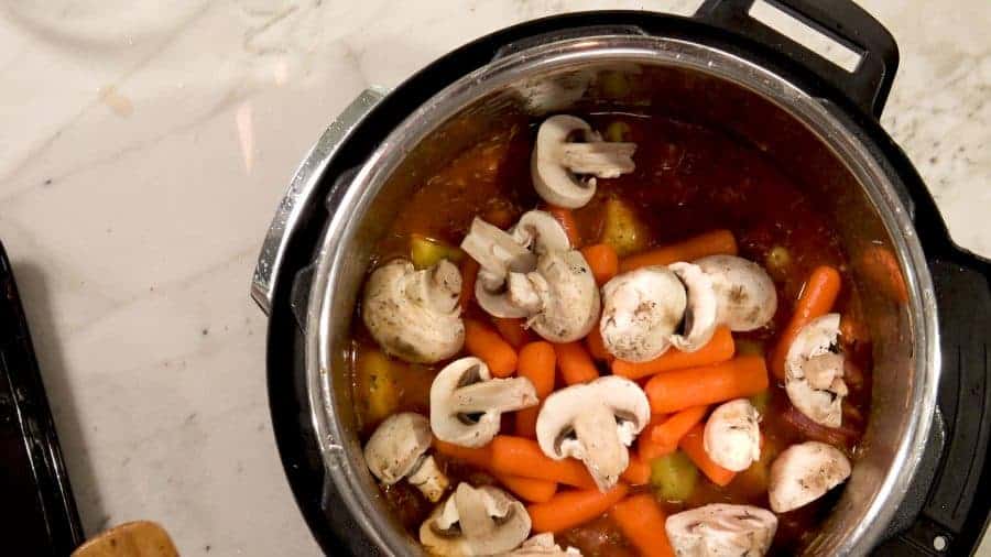 Overhead shot of carrots, mushrooms and potatoes added to the Instant Pot.