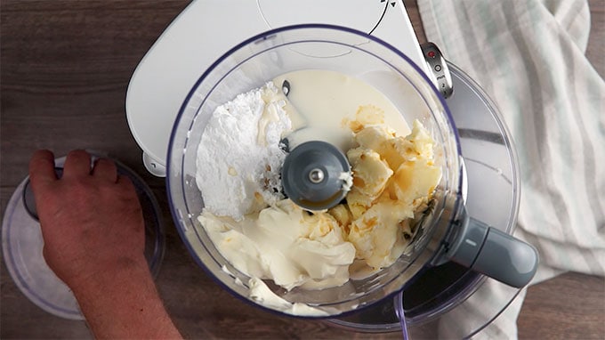 Overhead shot of the ingredients of the cream cheese frosting in a food processor.