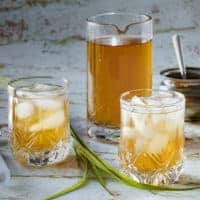 Pitcher of lemongrass tea with two glasses with ice and tea in them in the front