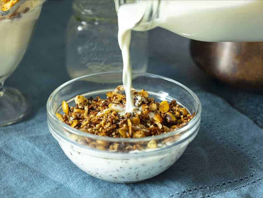 A bowl of Granola with milk being poured into it.