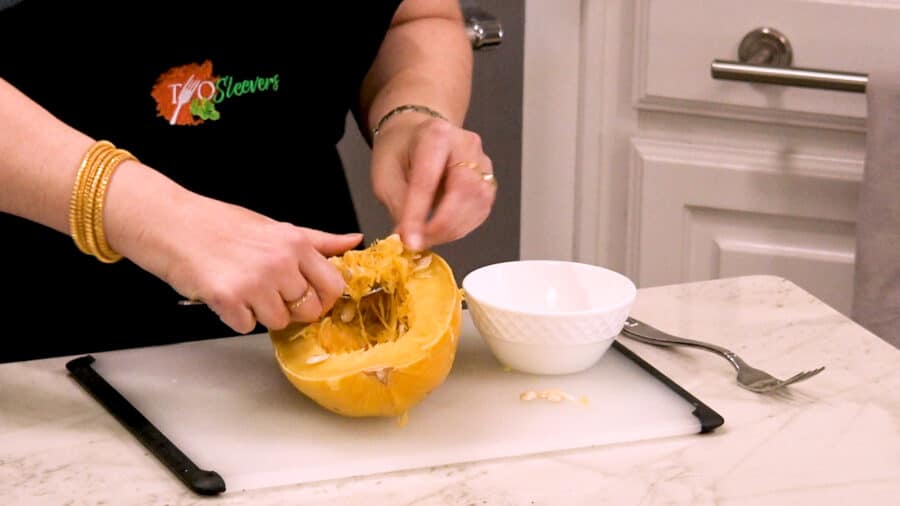 Side shot of removing the seeds from the spaghetti squash with a spoon.