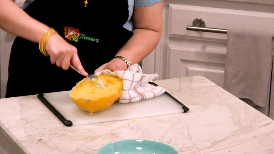 Side shot of using the tines of a fork to create long spaghetti squash strands.