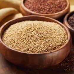 Three wooden bowls filled with different varieties of quinoa