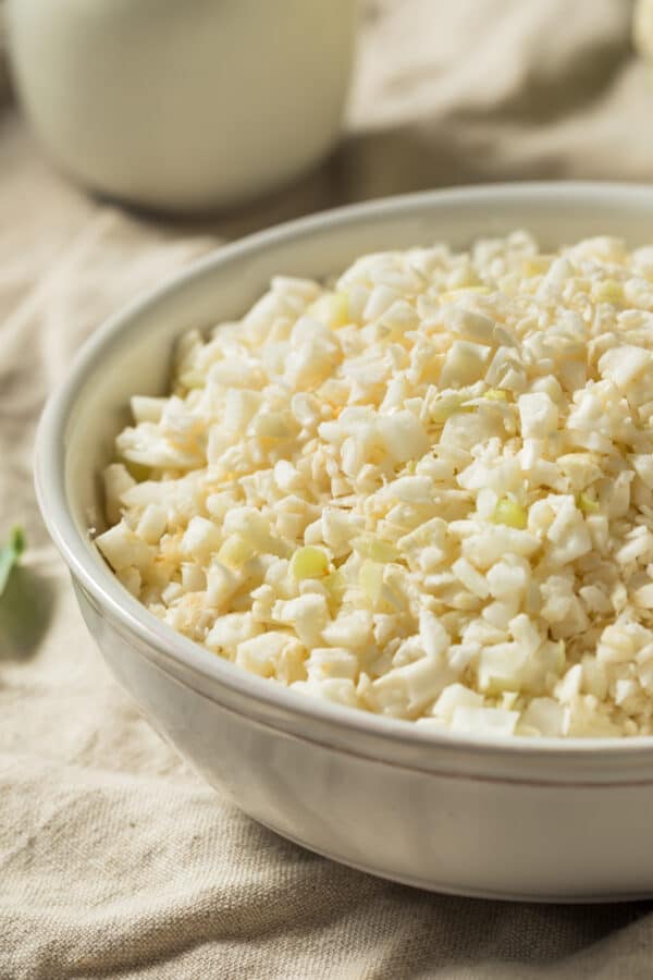 Close up of cauliflower rice in a white bowl ready to be cooked