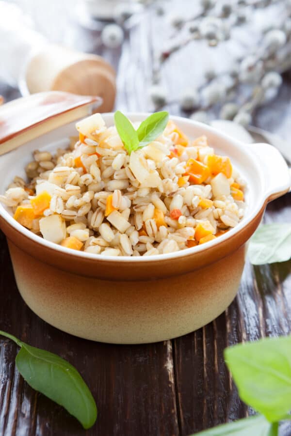 Cooked barley with carrots in an orange crock
