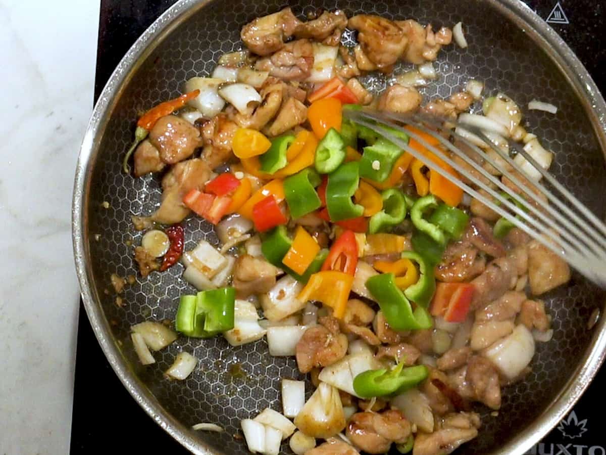 diced chicken and vegetables cooked in a skillet with a metal spatula
