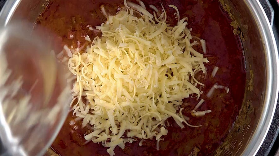 Overhead shot of adding the shredded cheese to the cooked soup.