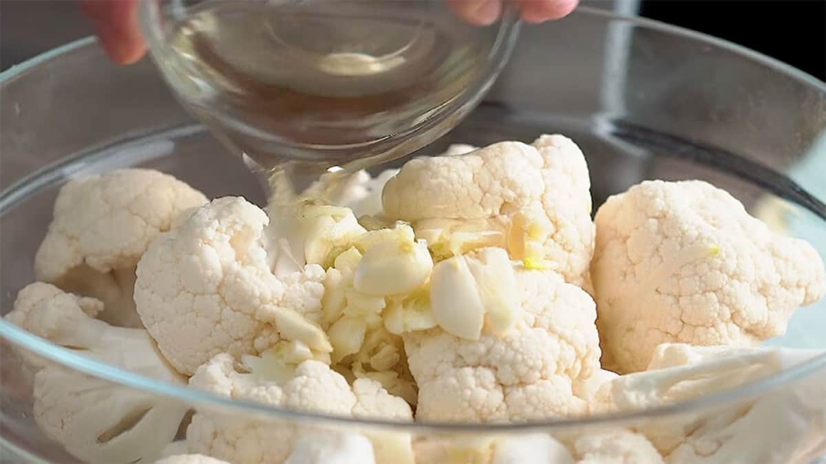 pouring vegetable oil over the top of cauliflower florets