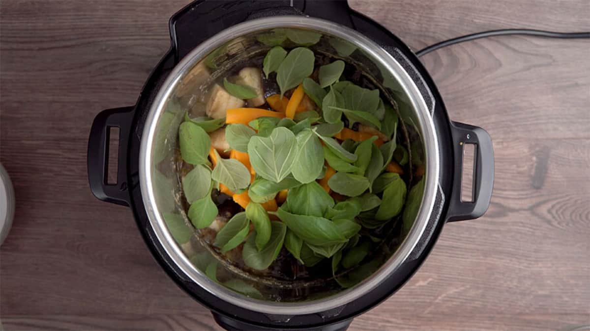 fresh basil leaves over cooked thai curry in an instant pot