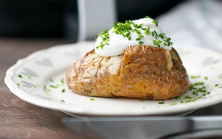 Side shot of a baked potato on a white plate