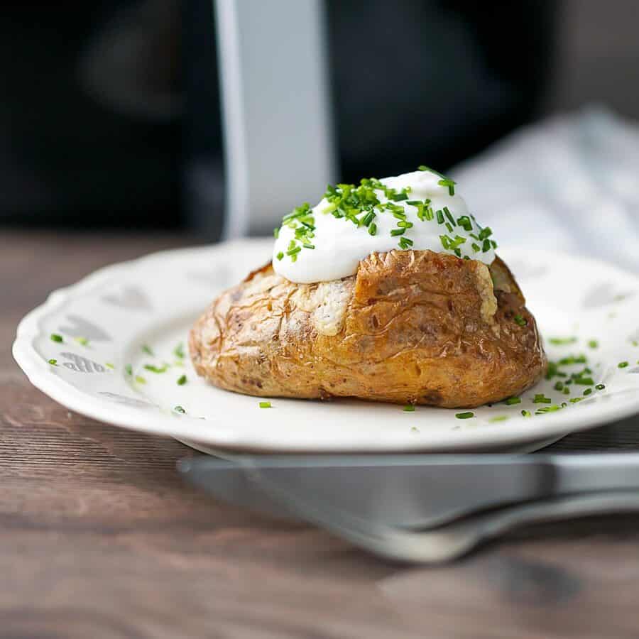 Side shot of a baked potato on a white plate