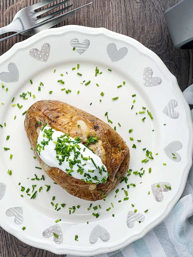 Overhead shot of a baked potato garnished with herbs