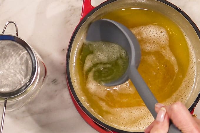 showing the perfect color for ghee, with a ladle scooping out liquid, homemade ghee