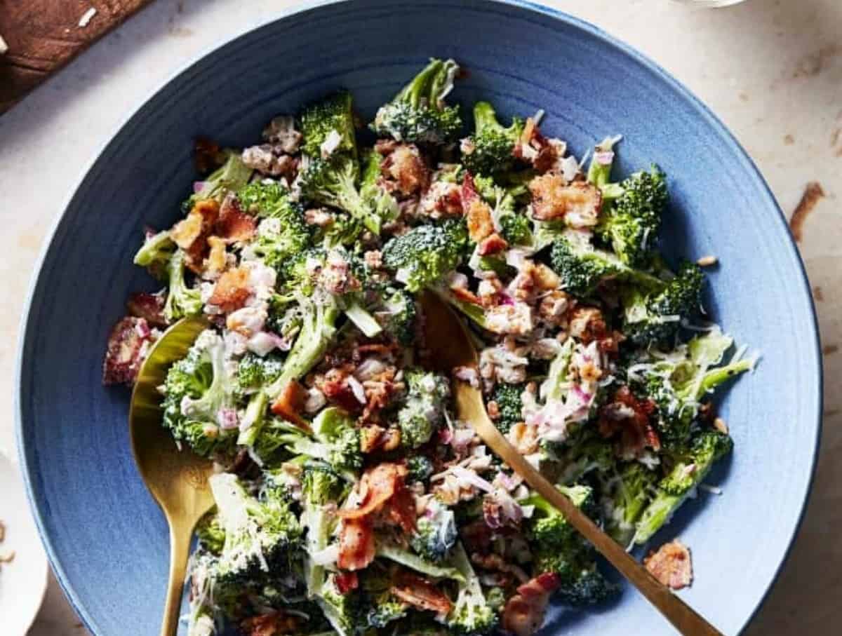 Overhead Image of Keto Broccoli Salad on a light blue plate with golden serving spoons.