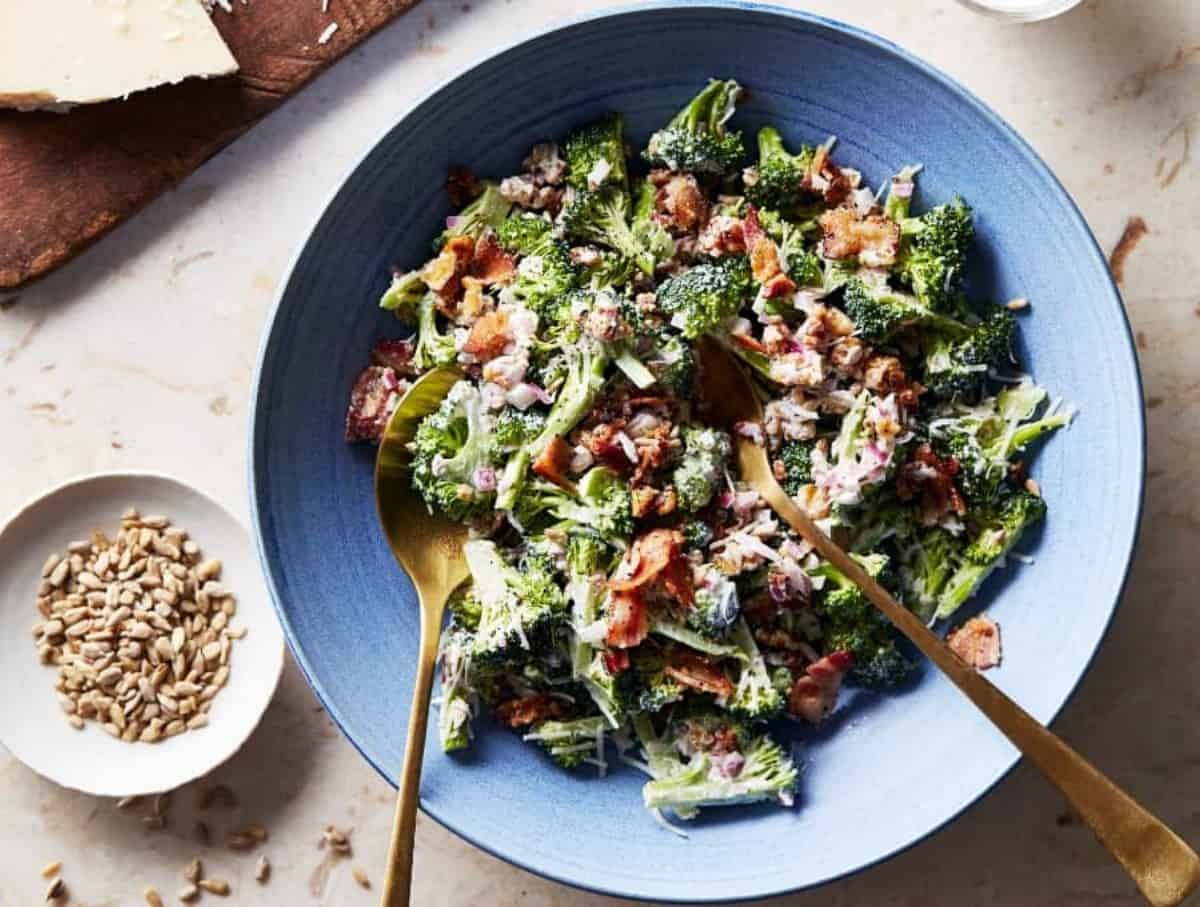 Overhead Image of Keto Broccoli Salad on a light blue plate with golden serving spoons.