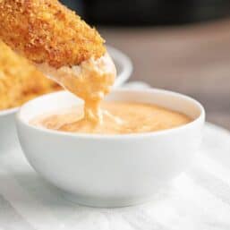 A Keto Chicken Tender being dipped in a white bowl of Big Mac Sauce