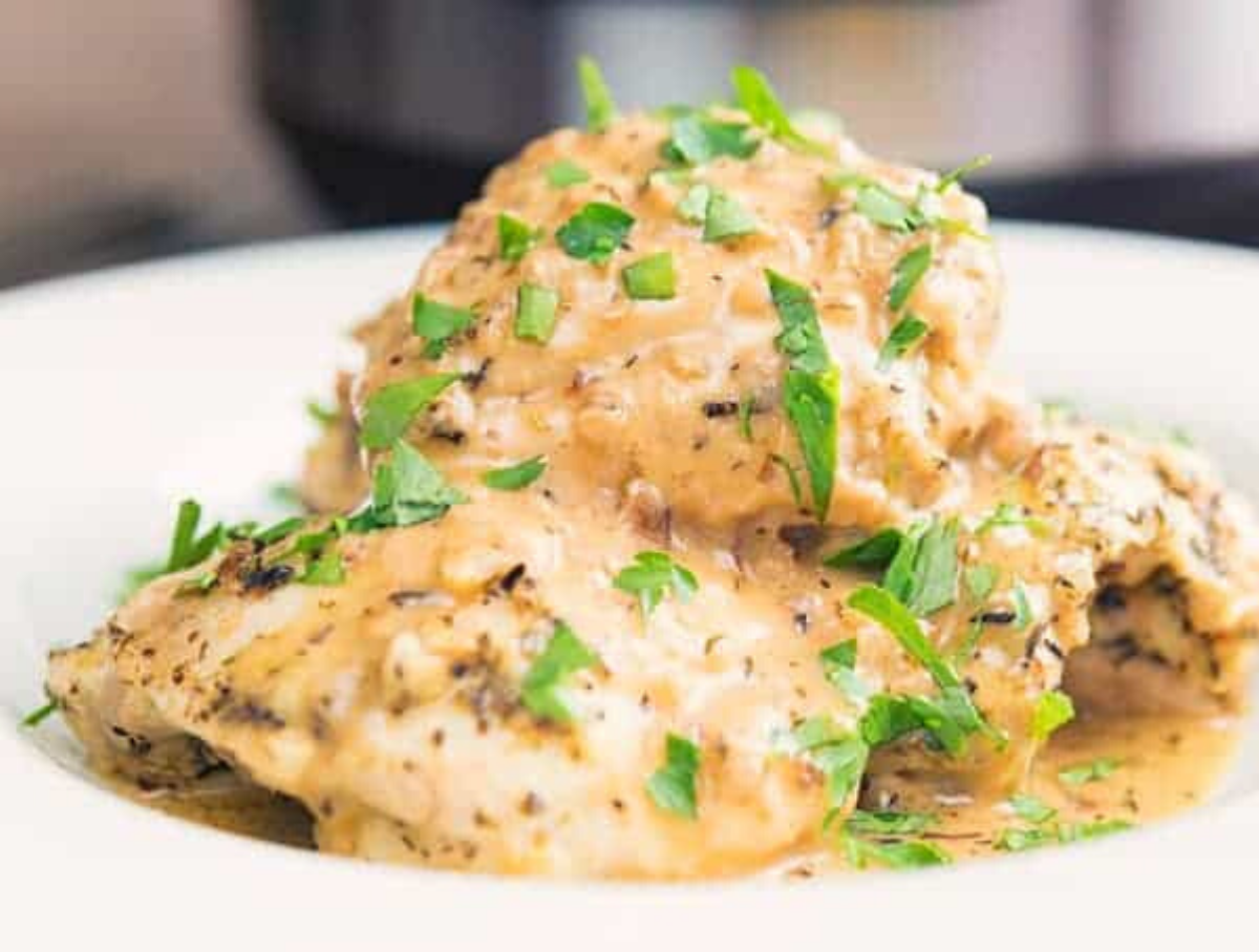 French Garlic Chicken served in a white bowl garnished with parsley.