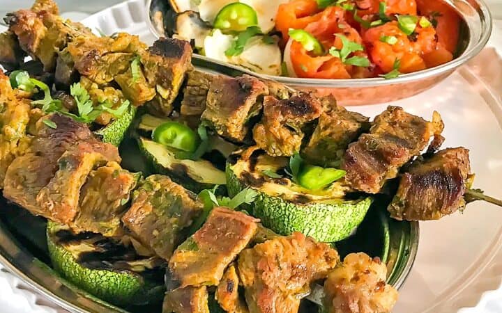 Grilled beef kebabs served on top of vegetables