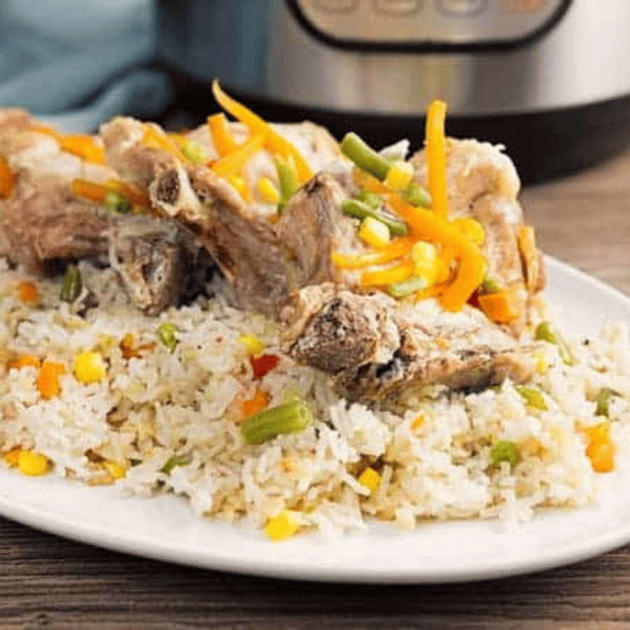 Close up image of Instant Pot Pork Chops and Rice with an Instant Pot in the background