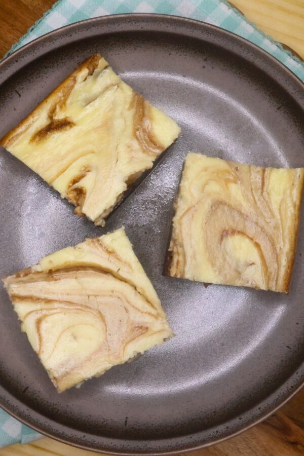 Overhead image of three Keto Cheesecake Brownies on a brown plate