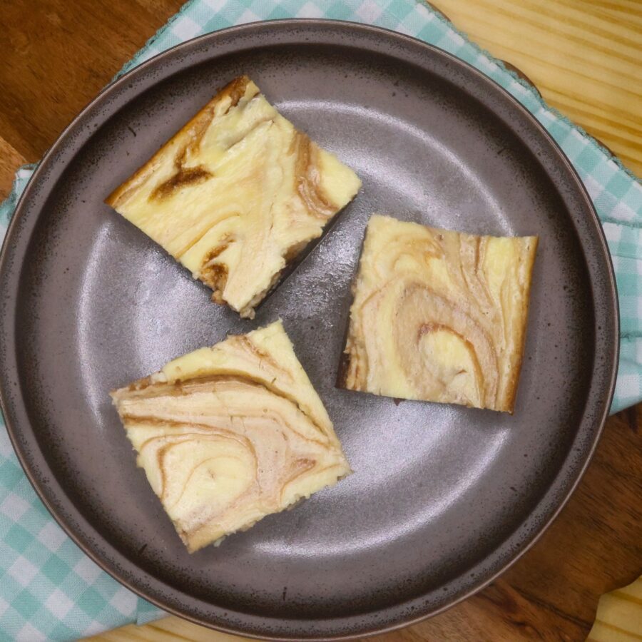 Overhead image of three Keto Cheesecake Brownies on a brown plate