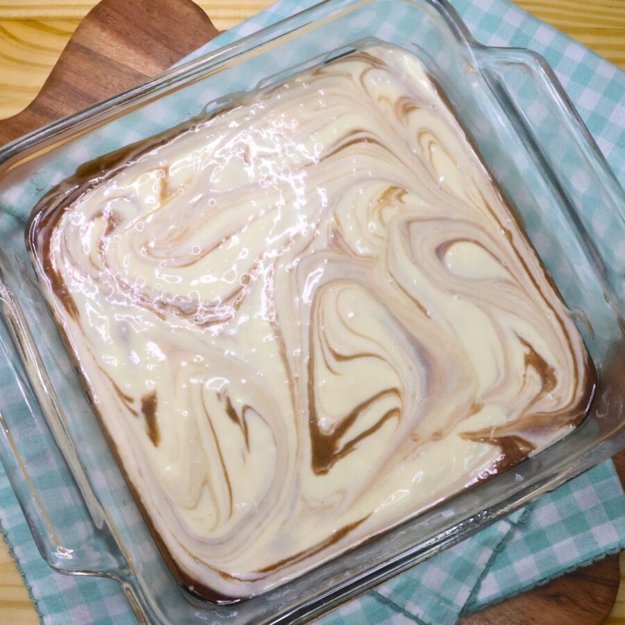 Keto Cheesecake Brownie batter swirled in a glass pan
