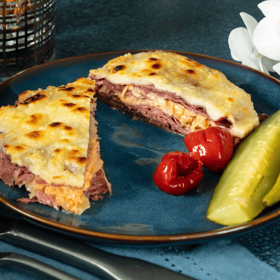Reuben Casserole on a blue plate with pickles and cherry tomatoes