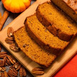 Gluten Free Pumpkin Bread on a cutting board with pumpkin and pecan garnish