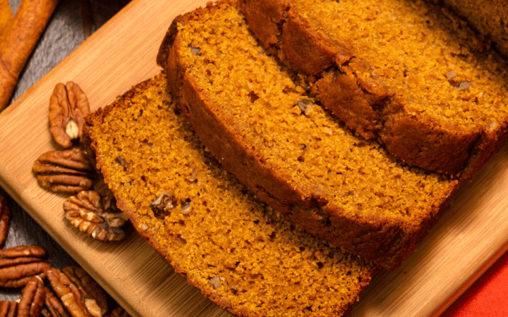 Gluten Free Pumpkin Bread on a cutting board with pumpkin and pecan garnish
