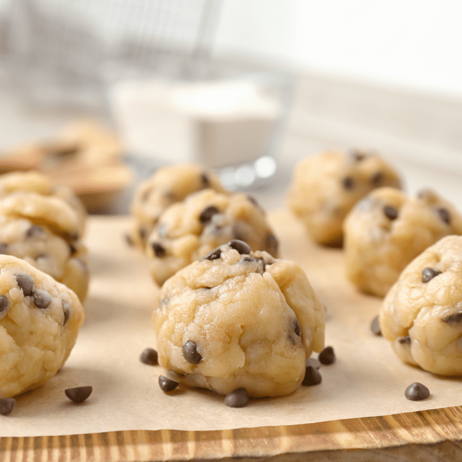 Cookie dough bites on parchment paper with mini chocolate chips laying around them