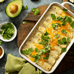 Keto Chicken Enchiladas in a casserole dish surrounded by garnishes