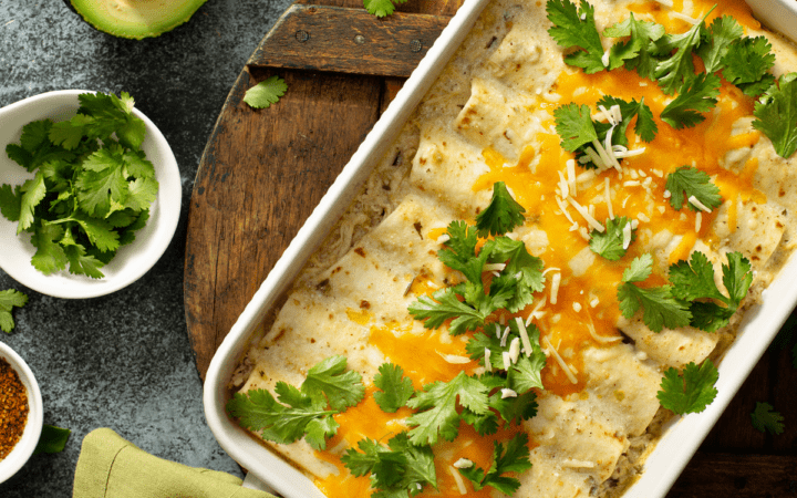 Keto Chicken Enchiladas in a casserole dish surrounded by garnishes