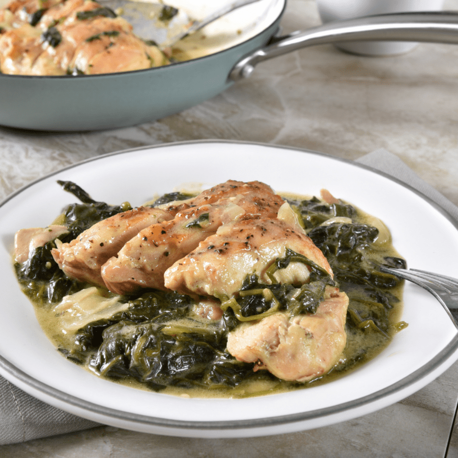 Chicken Florentine Served on a white plate with more in a skillet in the background