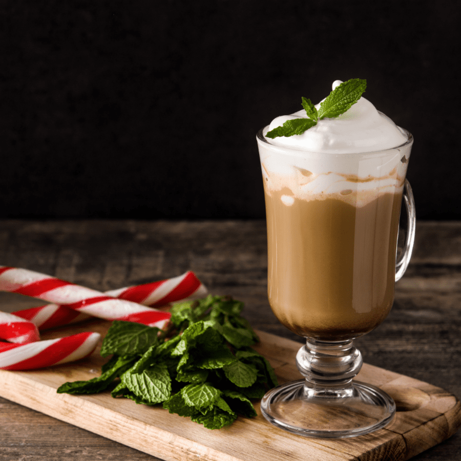 Peppermint Mocha in a clear mug next to fresh peppermint and candy canes