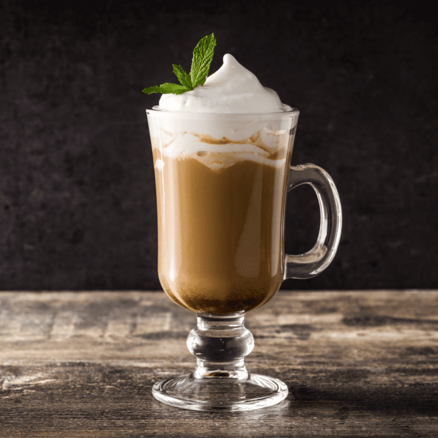 Peppermint mocha in a glass mug topped with whipped topping and a sprig of fresh peppermint