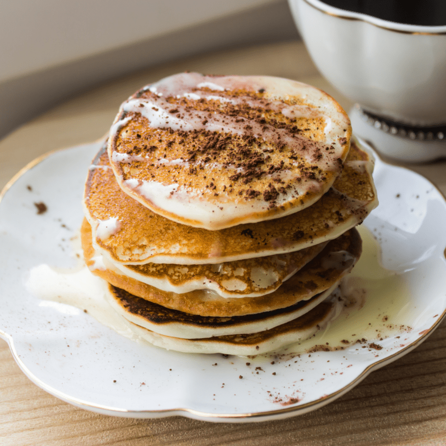 A stack of protein pancakes on a white plate sprinkled with cinnamon
