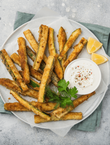 Air Fryer Zucchini Fries on a white plate with dipping sauce