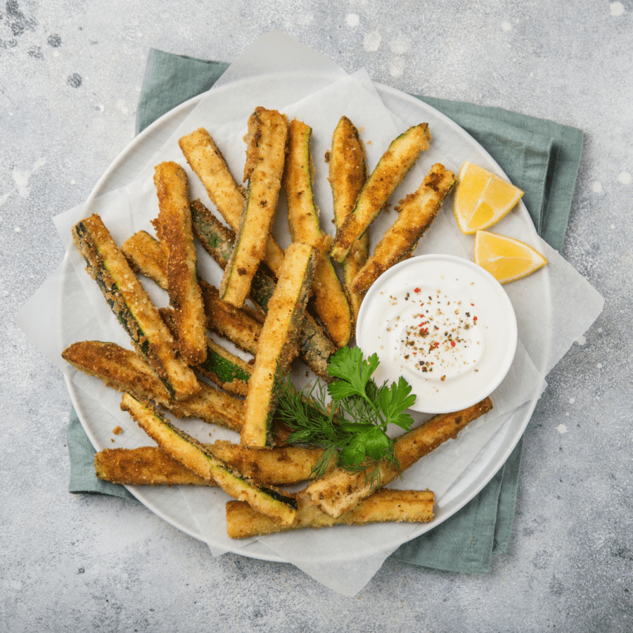 Air Fryer Zucchini Fries on a white plate with dipping sauce