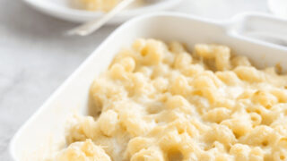 Panera mac and cheese in a baking dish with a serving on a plate in the background