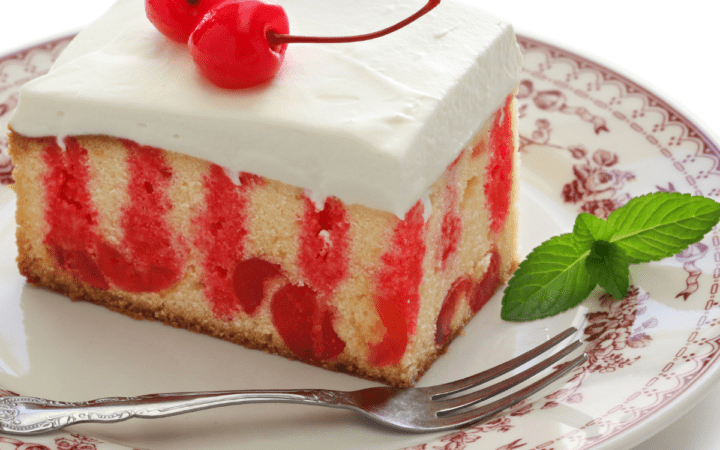 Cherry Poke Cake on a red and white plate with cherry and mint garnish