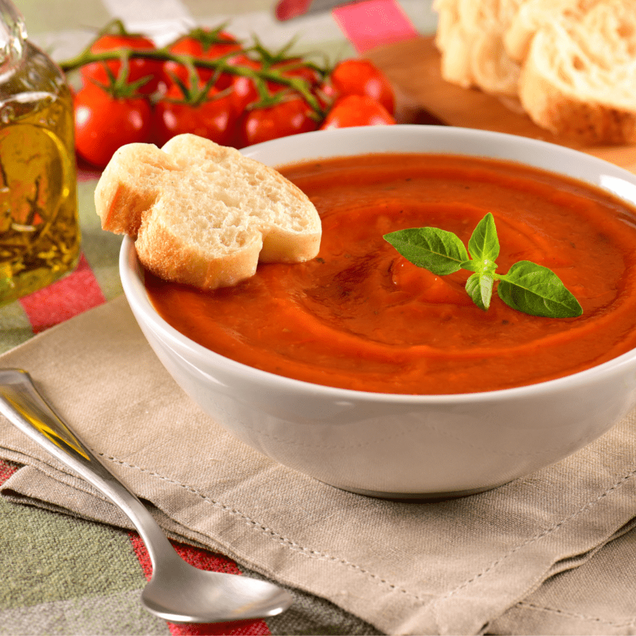 Pomodoro Sauce in a white bowl with a garnish of fresh herbs and crispy bread