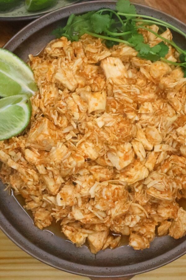 Instant Pot Salsa Chicken on a plate with cilantro and sliced lime