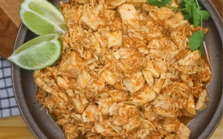 Instant Pot Salsa Chicken on a plate with cilantro and sliced lime