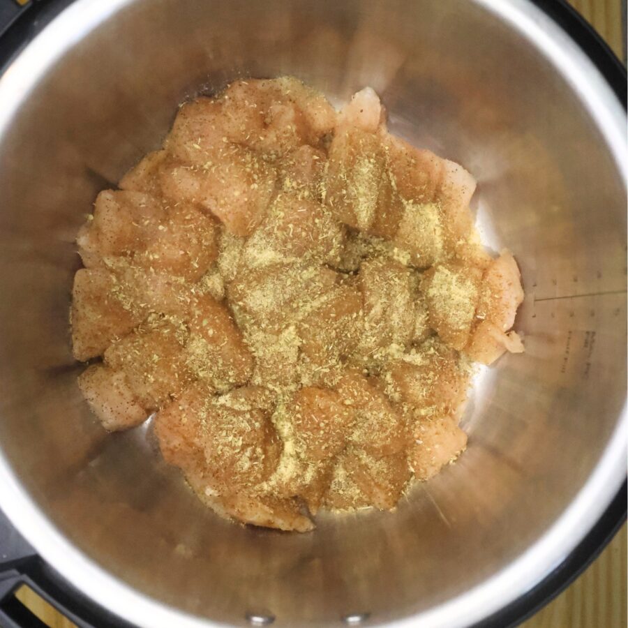 Diced chicken in an Instant Pot liner with spices on top