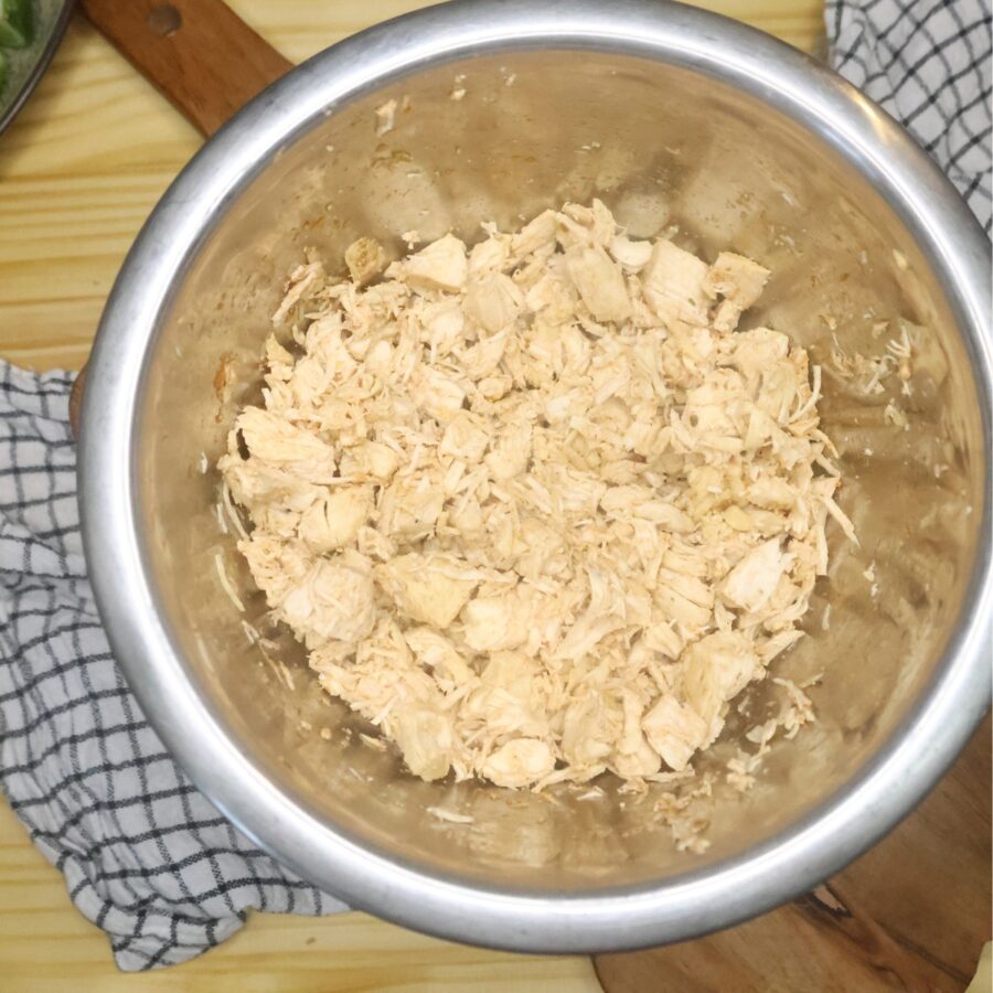 Overhead image of shredded chicken in a stainless steel bowl
