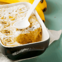 Banana Pudding Cake in a dark blue baking dish with a spoon on top